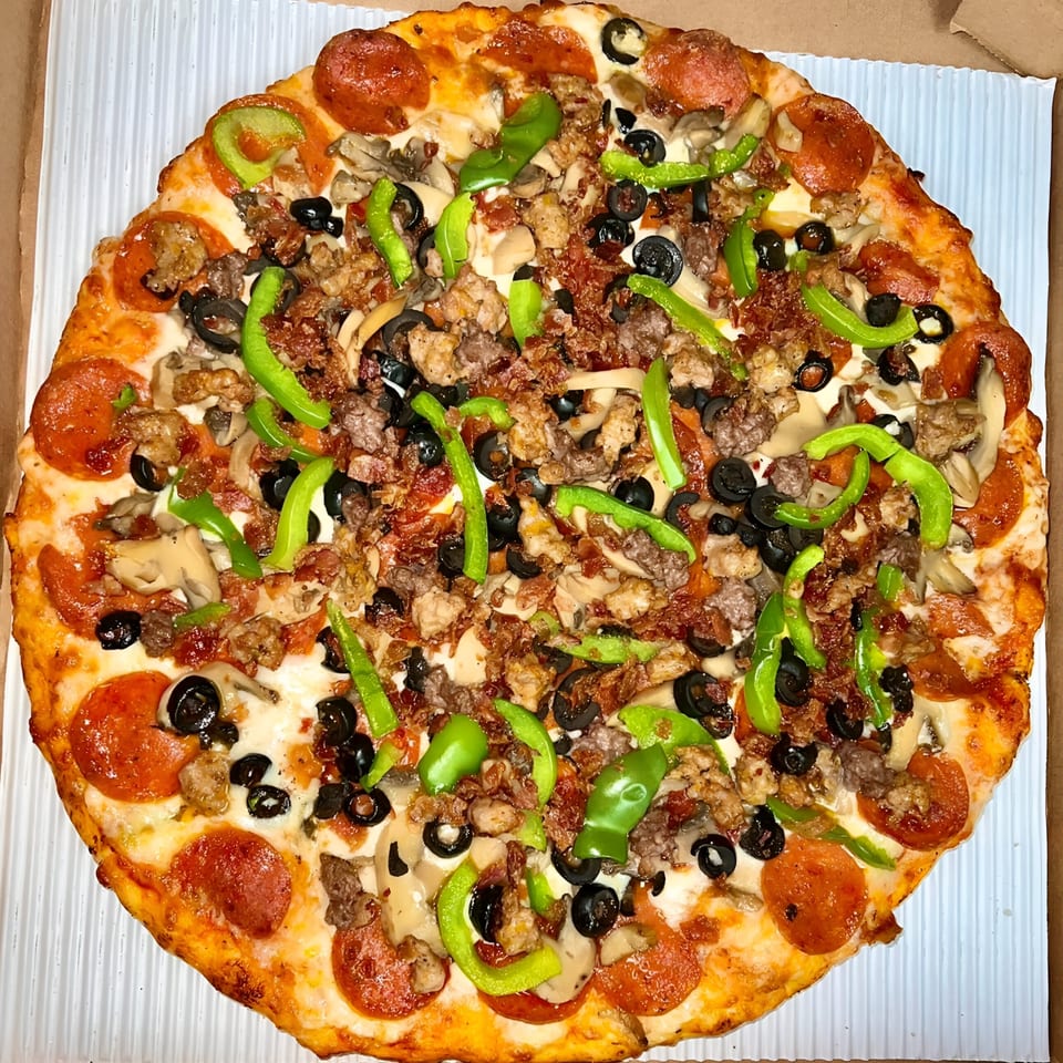 A Sunnyside Pizza with pepperoni, sausage, mushrooms, black olives, and green peppers.