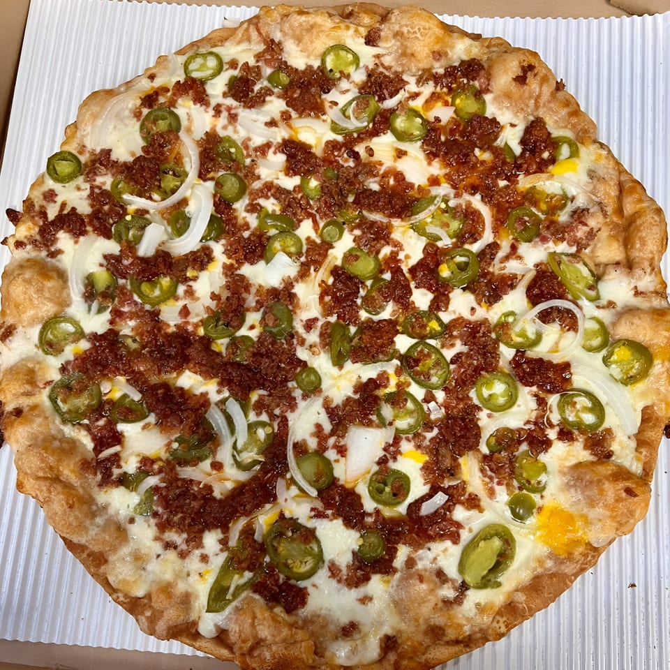 Sunnyside Pizza's whole pizza with white sauce, chorizo, jalapeños, and onions in a box.