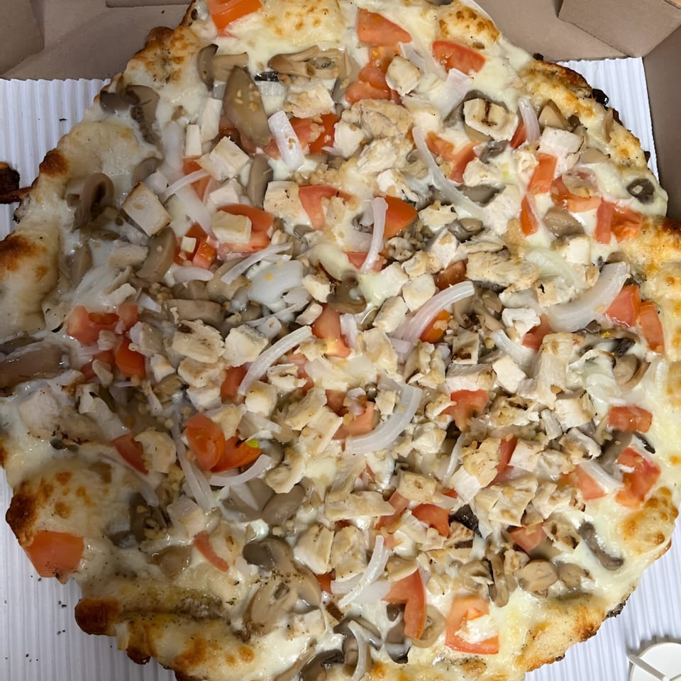 Sunnyside Pizza's white pizza with chicken, mushrooms, onions, and tomatoes in a box.