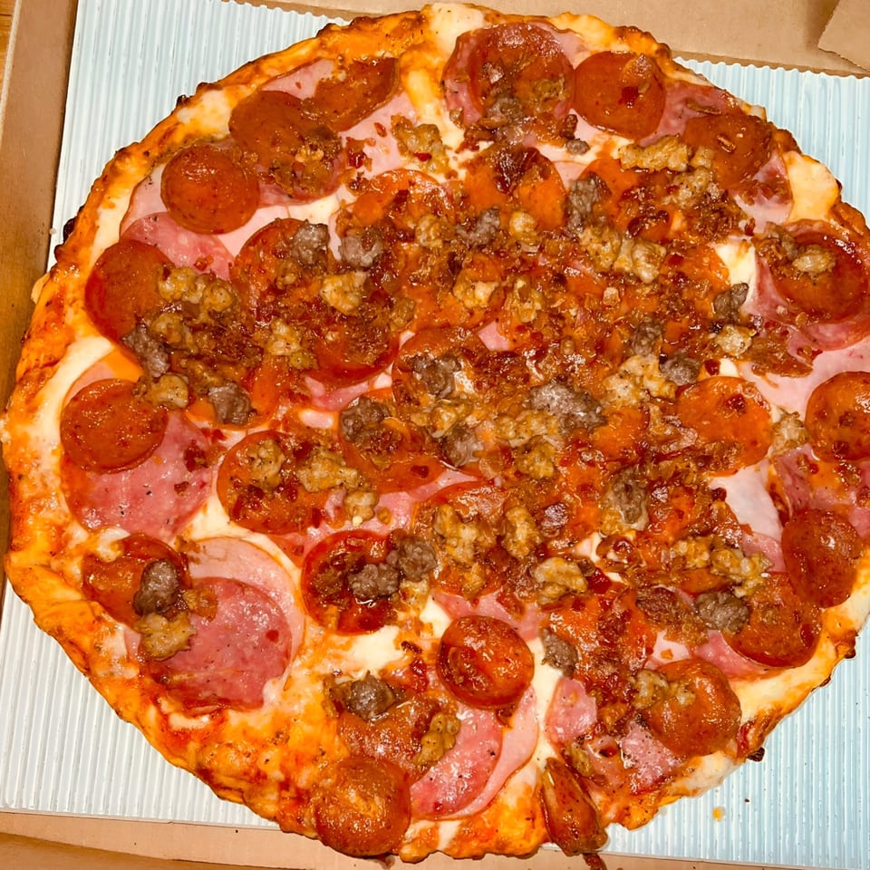 A Sunnyside Pizza with pepperoni, ham, and sausage, in a pizza box.